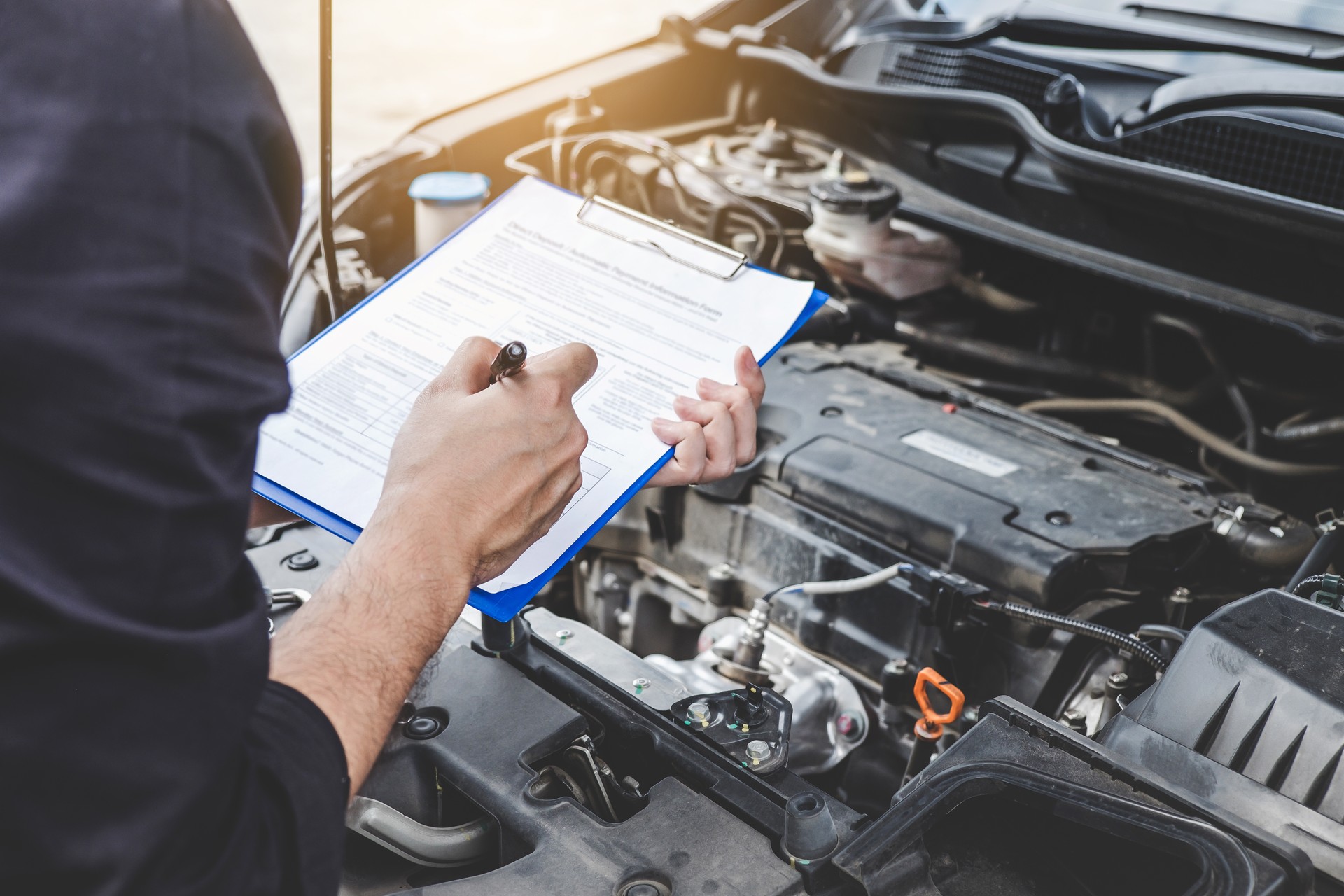 Services car engine machine concept, Automobile mechanic repairman checking a car engine with inspecting writing to the clipboard the checklist for repair machine, car service and maintenance